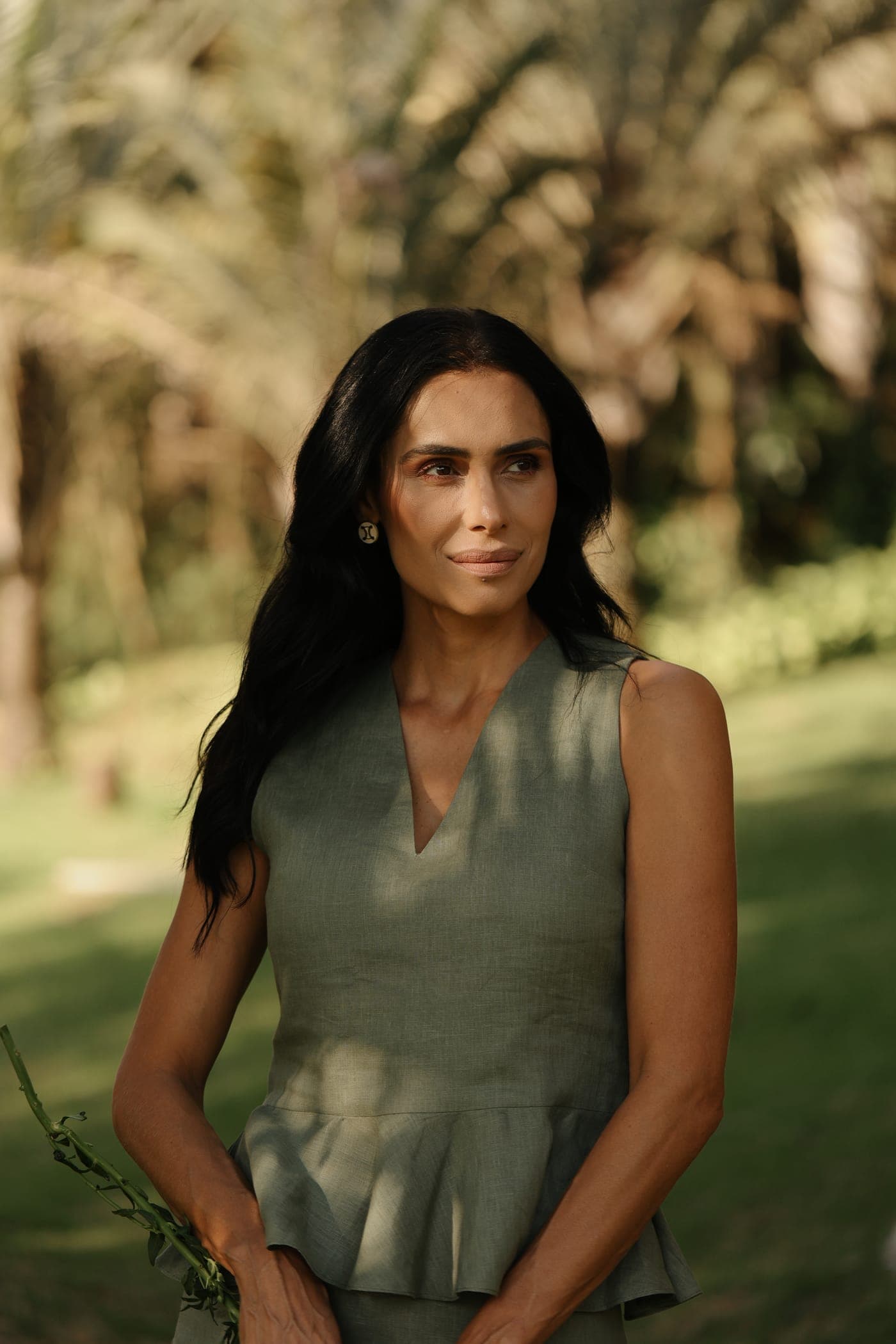 Sorriso leve em campo aberto, vestido verde-oliva